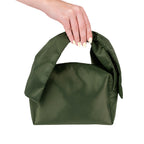 Grace & Gild Victoria Bow Make Up Bag in Olive shown being carried by its padded bow-style handle.