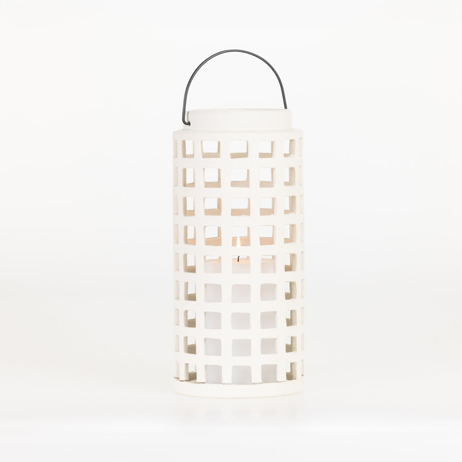 White ceramic lantern with a square cut-out design, black metal carry handle and a lit candle inside, shown on a white background.