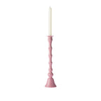 Blush pink decorative candle holder displayed with a tall white taper candle against a white background.