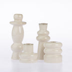 Four glossy ceramic candle holders in a warm cream or off-white glaze, arranged on a seamless white background.