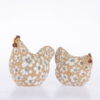 Two decorative ceramic chickens on a white background, one larger rooster and one smaller hen, both in a tan color with a white floral pattern and brown accents.