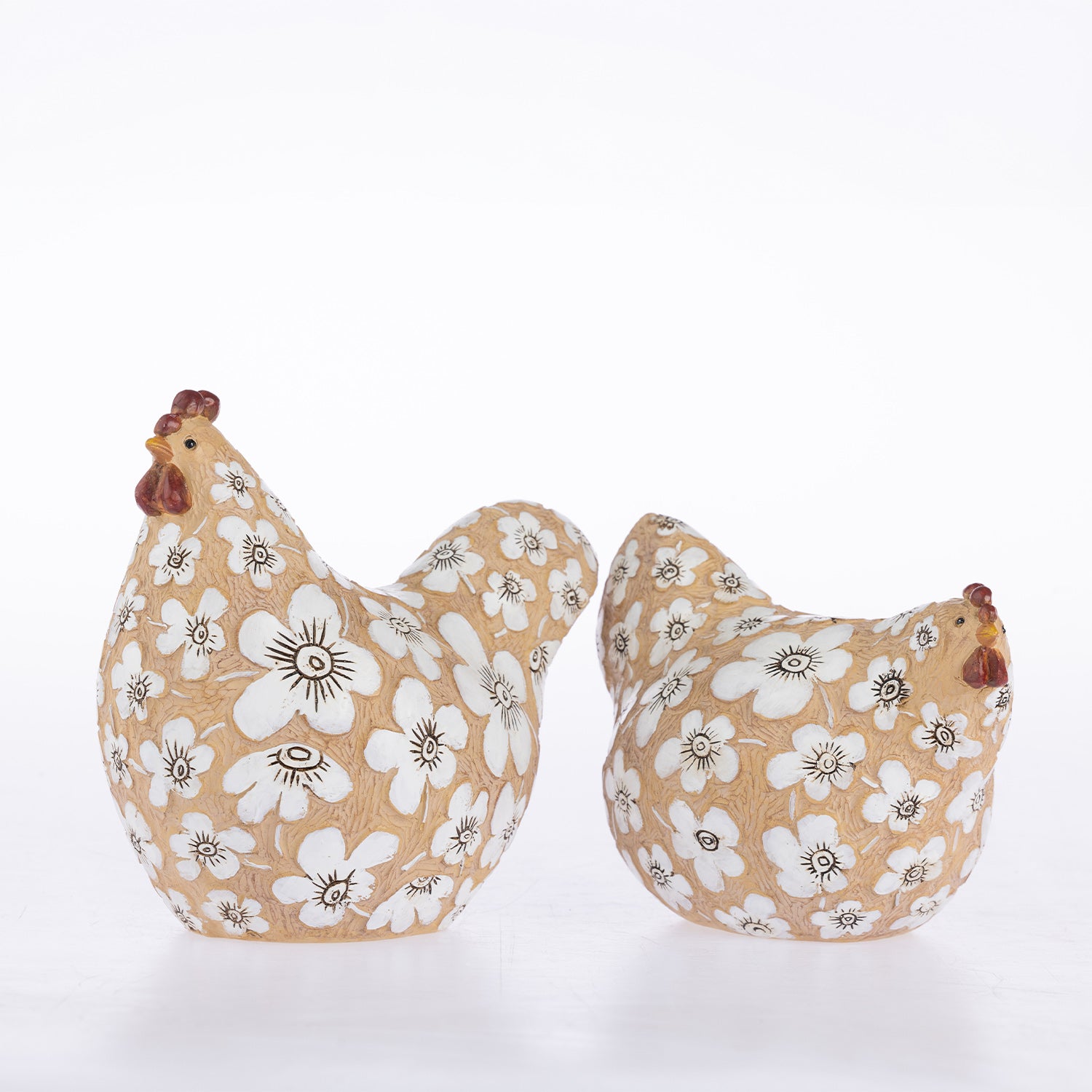 Two decorative ceramic chickens on a white background, one larger rooster and one smaller hen, both in a tan color with a white floral pattern and brown accents.