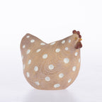 A decorative ceramic chicken figurine with a textured tan body, white polka dots, and reddish-brown comb and wattle, set against a plain white background.