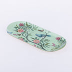 An oval-shaped decorative tray with a light mint green background, decorated with a delicate floral and bird pattern featuring pink flowers, green leaves, and a bluebird.