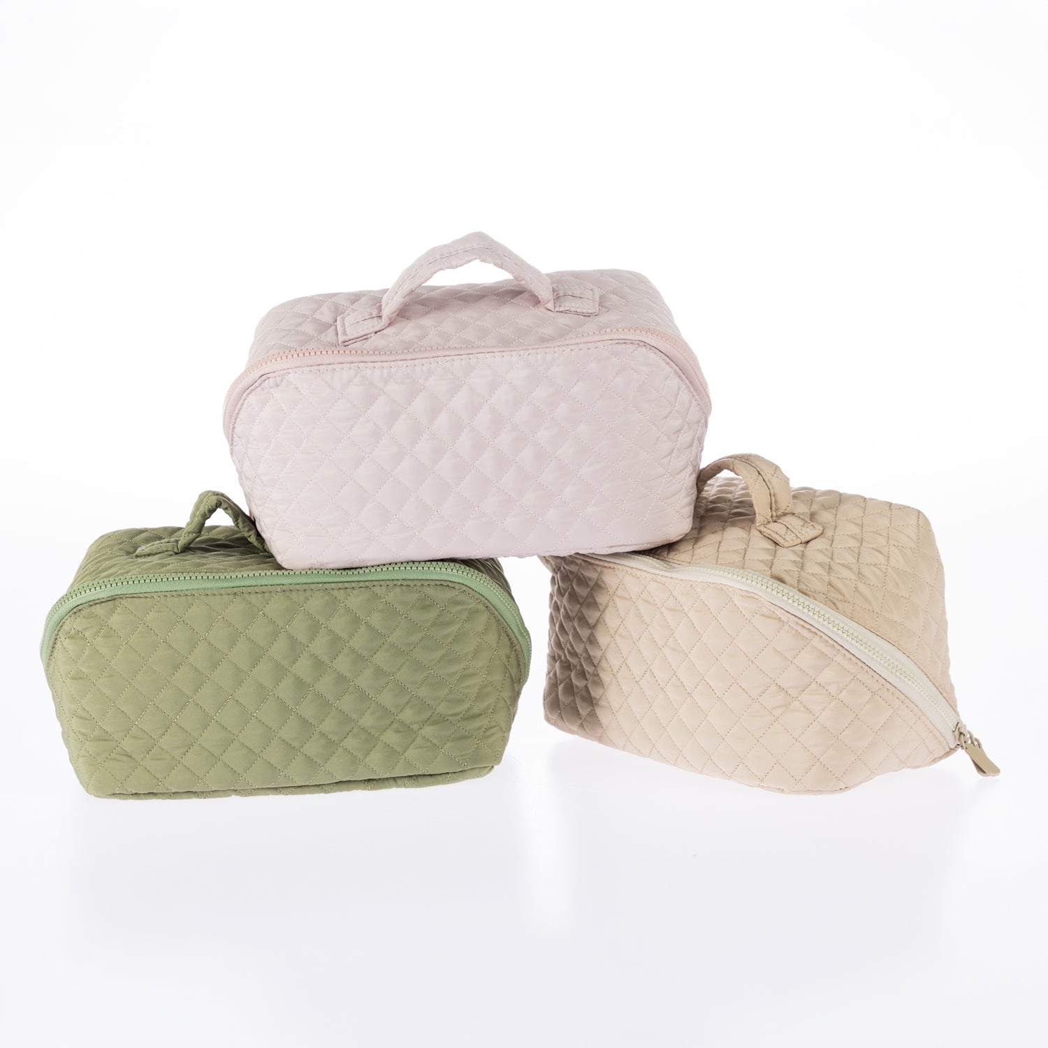 Three quilted toiletry bags in pale lilac, light green, and tan with zip closures and carry handles.