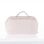Tan quilted toiletry bag with a zip-around closure and top carry handle on a white background.