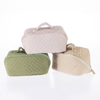 Three quilted toiletry bags in pale lilac, light green, and tan with zip closures and carry handles.