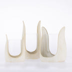 Three ivory textured candle holders in varying sizes with curved sculptural frames and clear glass inserts.