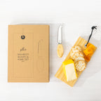 Gather 2 Piece Bamboo Board & Knife Set featuring a natural bamboo serving board with cheese, crackers, dried fruit and a matching cheese knife beside its packaging.