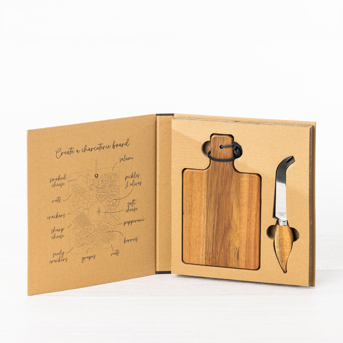 Gather 2 Piece Acacia Board & Knife Set displayed in open gift packaging with a paddle-shaped acacia board and stainless steel cheese knife with wooden handle.