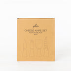 Gather 4 Piece Cheese Knife Set Acacia Black presented in a closed kraft cardboard gift box with illustrations of four cheese utensils.