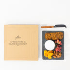 Gather 2 Piece Cheese Knife & Slate Board Set featuring a square black slate serving board with cheese, crackers, grapes, dried fruit and nuts alongside a cheese knife and packaging.