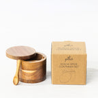 Gather Acacia Spice Container Set featuring a round natural acacia wood spice container with a removable lid, matching wooden spoon and kraft cardboard packaging.