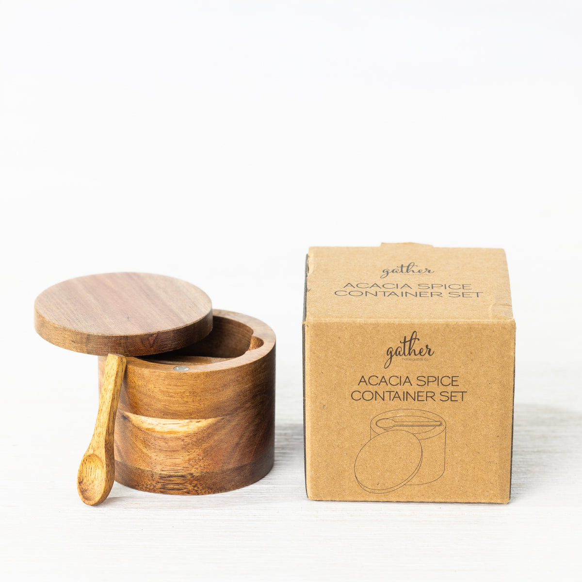 Gather Acacia Spice Container Set featuring a round natural acacia wood spice container with a removable lid, matching wooden spoon and kraft cardboard packaging.