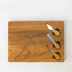 Gather 4 Piece Acacia Board & Knife Set featuring an engraved natural acacia wood serving board with three cheese utensils neatly stored in specially shaped recessed compartments.