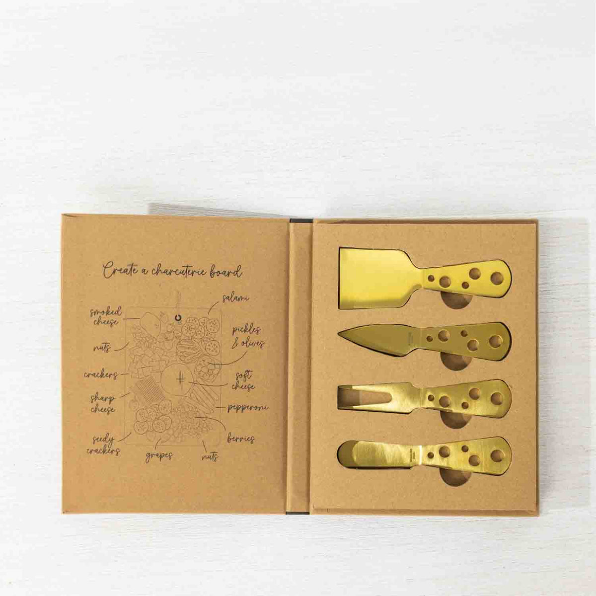 Gather 4 Piece Cheese Knife Set Gold displayed in open gift packaging with four gold-coloured cheese utensils and a charcuterie board illustration inside the box.