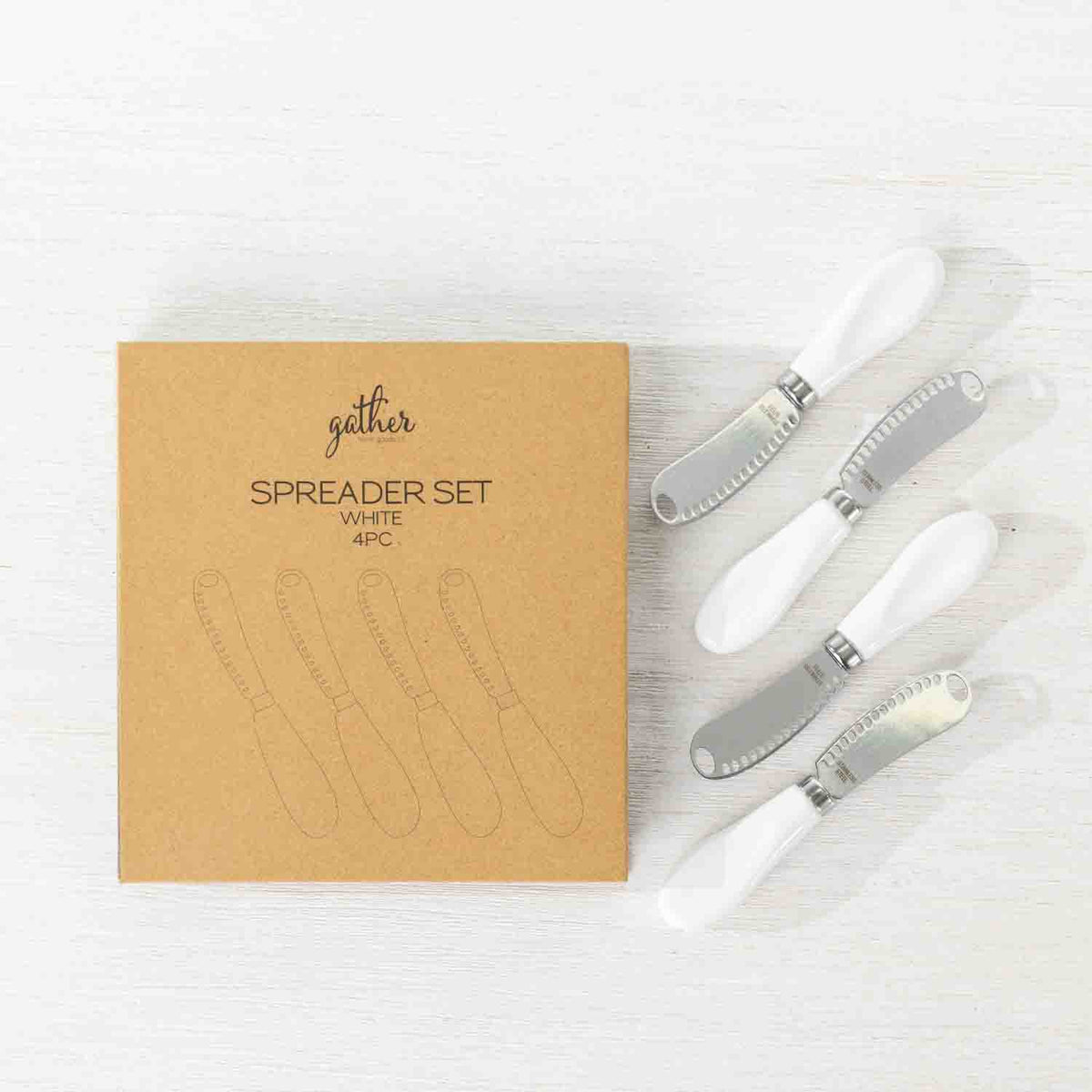 Gather 4 Piece Spreader Set White featuring four stainless steel spreaders with white handles displayed beside the kraft cardboard gift packaging.
