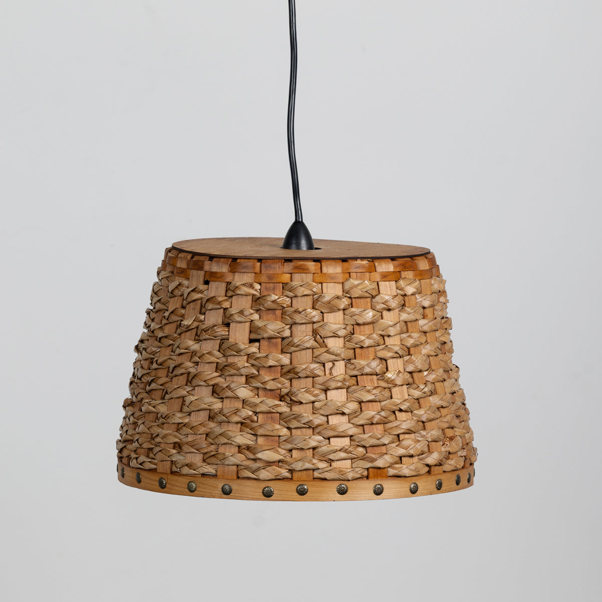 A woven natural fiber pendant lampshade with a black hanging cord, shown against a plain light gray background.