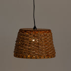 A woven natural fiber pendant lampshade with a black hanging cord, shown against a plain gray background with a warm light glowing through the textured weave.