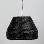 A black woven wicker pendant light shade suspended by a black cord against a light gray background.