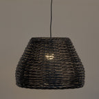 A dark woven wicker pendant light shade hanging from a black cord against a plain warm gray background.
