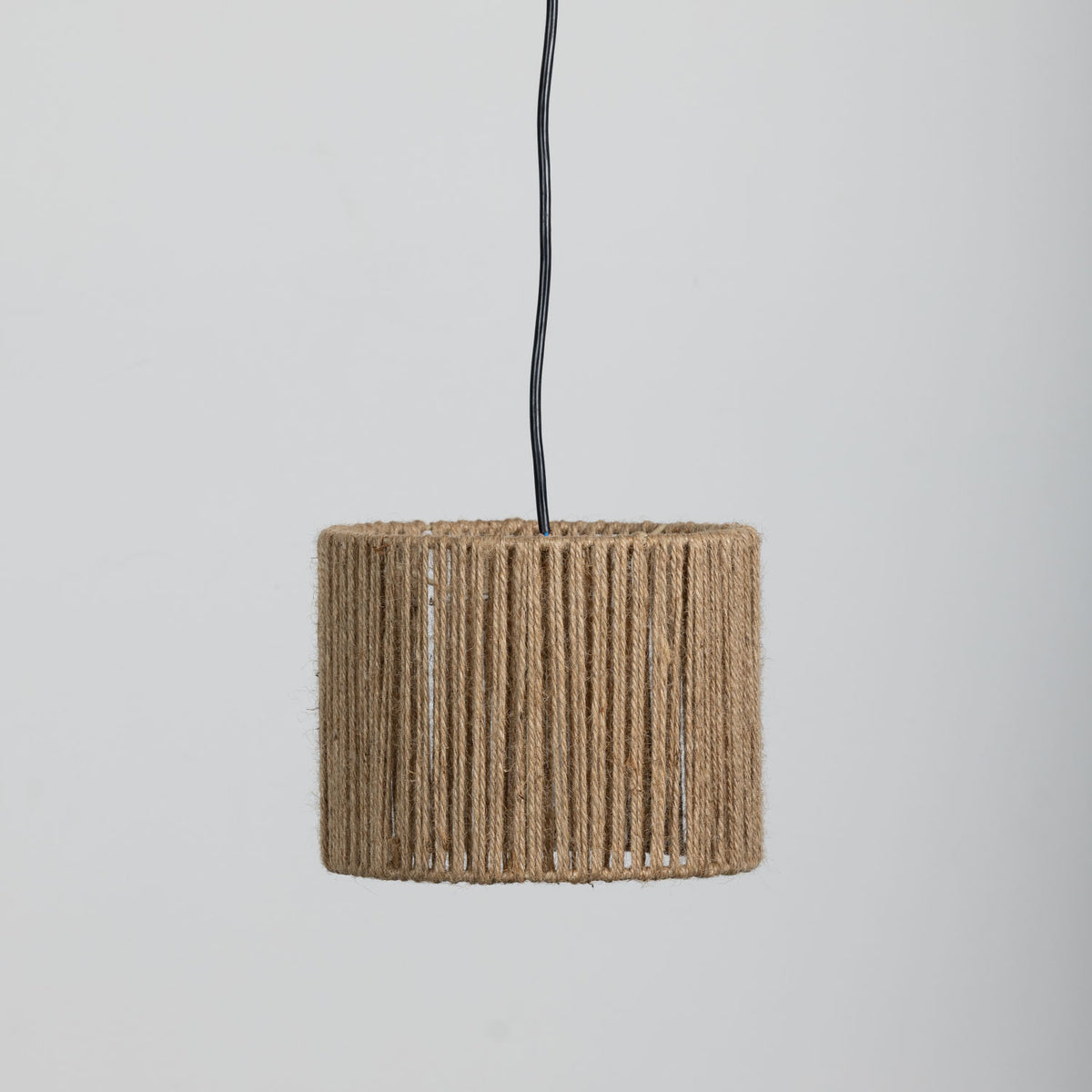 A cylindrical light shade wrapped in natural rope, suspended by a black cord against a plain light gray background.