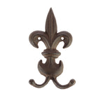 A decorative dark metal fleur-de-lis wall hook with two curved prongs is shown against a plain light background.