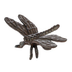 A decorative dark metal dragonfly ornament with textured wings and a segmented body is shown against a plain light background.