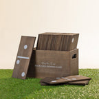 Play The Field backyard domino game featuring oversized wooden dominoes stored in a wooden carry crate on grass.