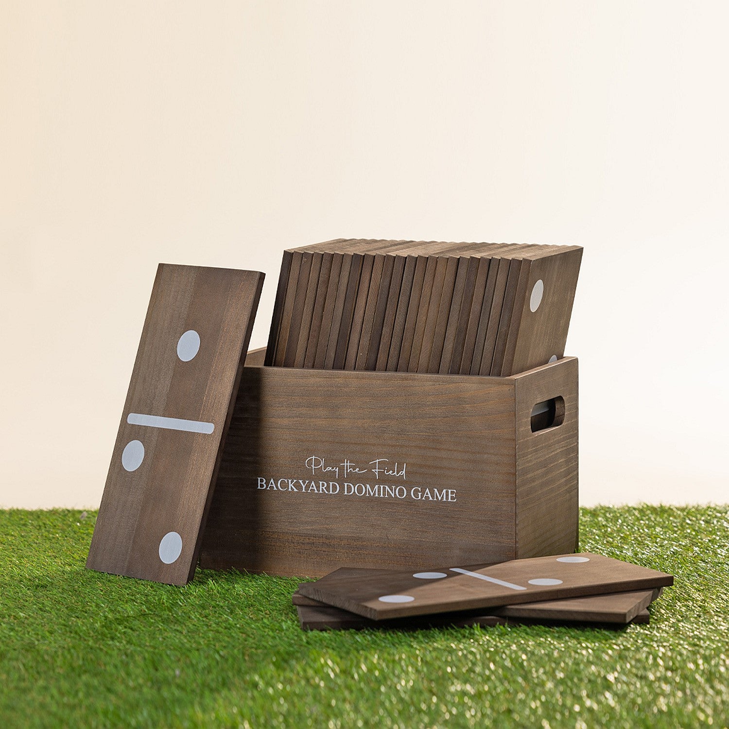 Play The Field backyard domino game featuring oversized wooden dominoes stored in a wooden carry crate on grass.