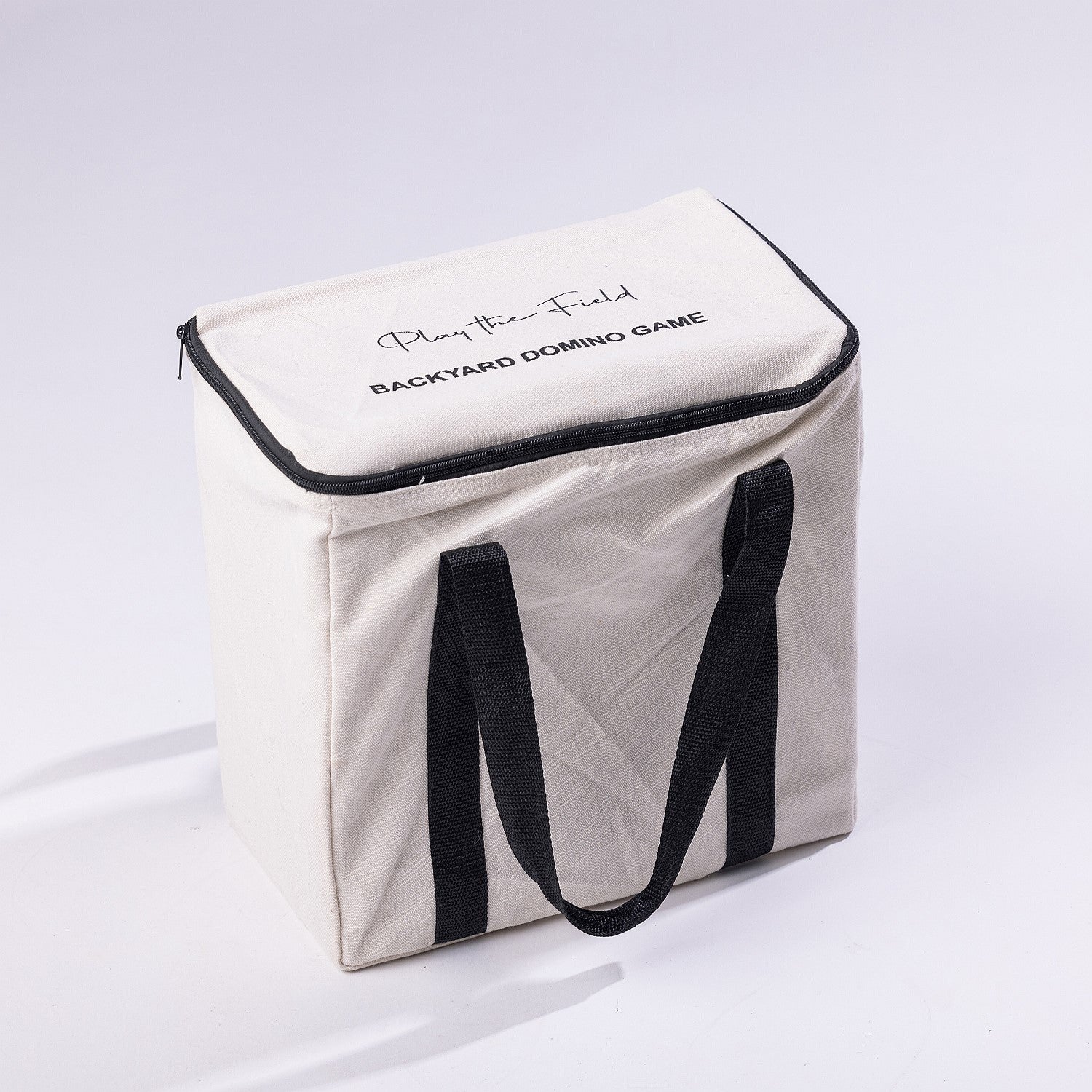 Play The Field backyard domino game packed in a natural canvas carry bag with black handles and zip closure.