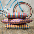 Stack of colorful striped pillows with a bicycle in the background