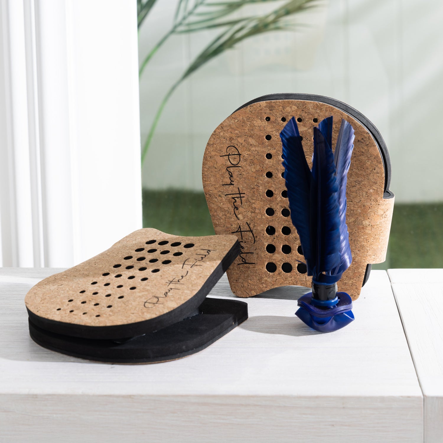 Play The Field shuttlecock hand paddle game set with two cork paddles and a blue shuttlecock displayed on a tabletop.