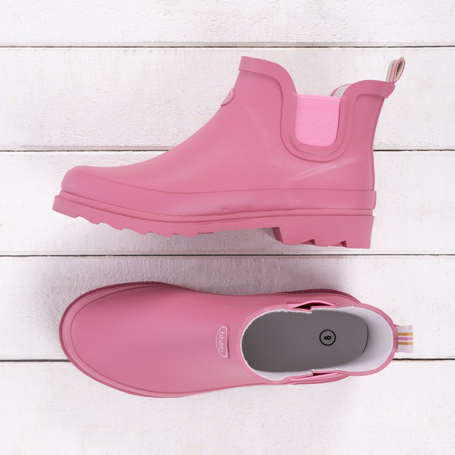 Wild rose pink ankle rain boot shown from the side and top, featuring elastic side panels, a rear pull tab and chunky treaded sole.