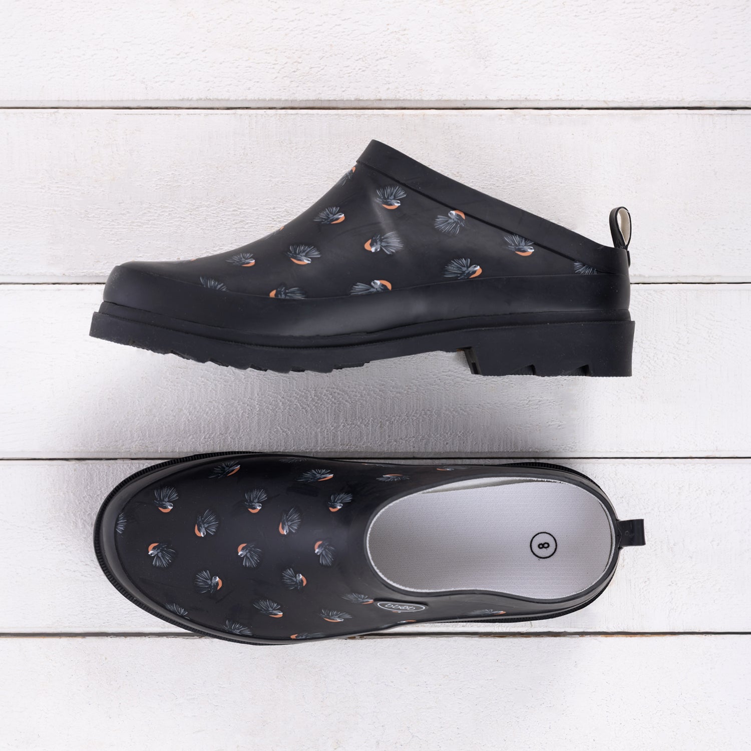 Outsidings Scuff Piwakawaka in Black, featuring a black slip-on design with scattered piwakawaka bird motifs and a chunky black sole.