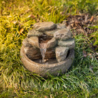 Close-up of the rock-effect LED water fountain in an outdoor garden setting, highlighting the cascading water feature and built-in LED light