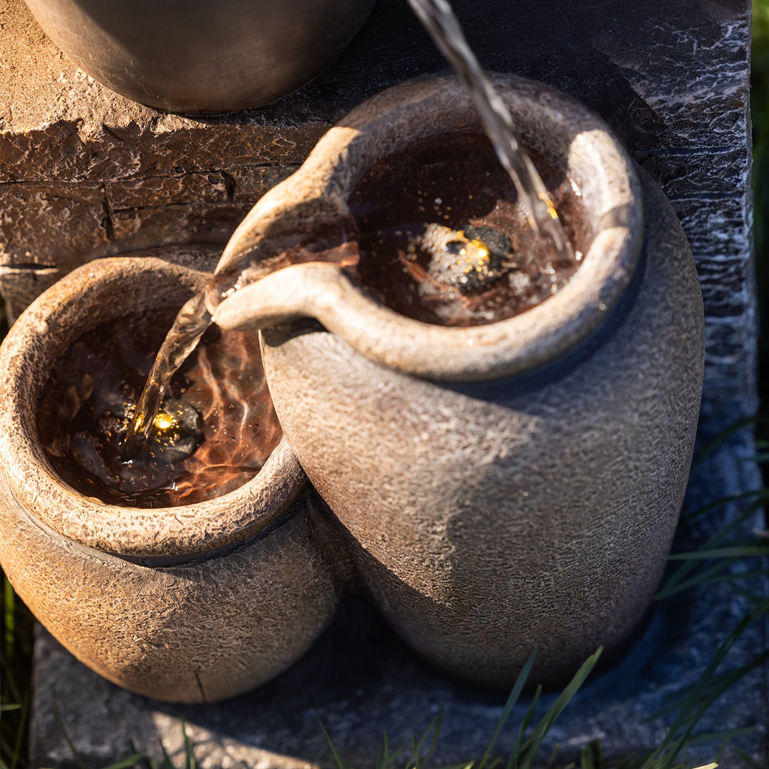 Close-up of the Outsidings Multiple Pot LED Fountain showing textured stone-look pots with cascading water flowing between the vessels.