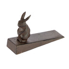 A decorative dark metal rabbit-shaped doorstop mounted on a wedge-shaped base is shown against a plain light background.
