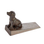 A decorative dark metal dog-shaped doorstop mounted on a wedge-shaped base is shown against a plain light background.