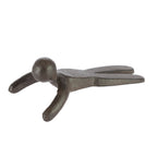 A dark metal doorstop shaped like a simplified human figure with outstretched arms is shown against a plain light background.