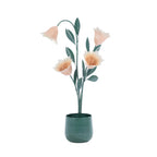 Green metal flower arrangement in a matching pot featuring soft peach flowers and decorative green leaves.