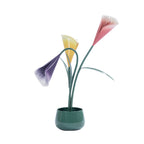 Green metal flower arrangement in a matching pot featuring pink, yellow and purple tulip-style flowers with decorative green leaves.