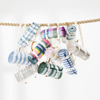 Multiple rolled picnic mats hung from a thick rope against a clean white background. 