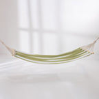 Green and white striped hammock suspended with wooden spreader bars against a light background.