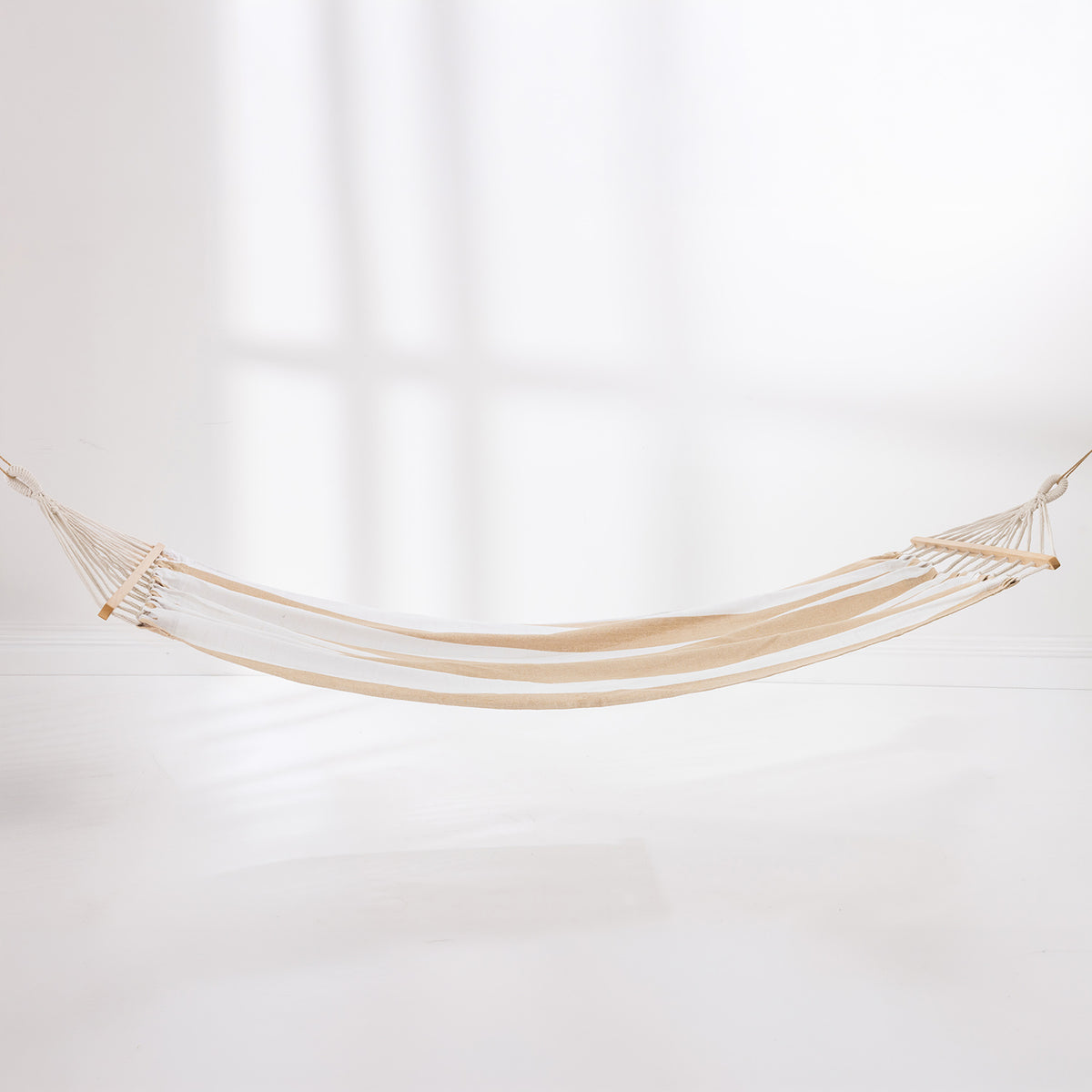 Natural and white striped hammock suspended with wooden spreader bars against a light background.