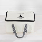 The outdoor game Kubb in a canvas bag with black trim, black-and-white striped handles.