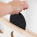 A close-up of a hand inserting a black round disc piece into a 4 in a row board.