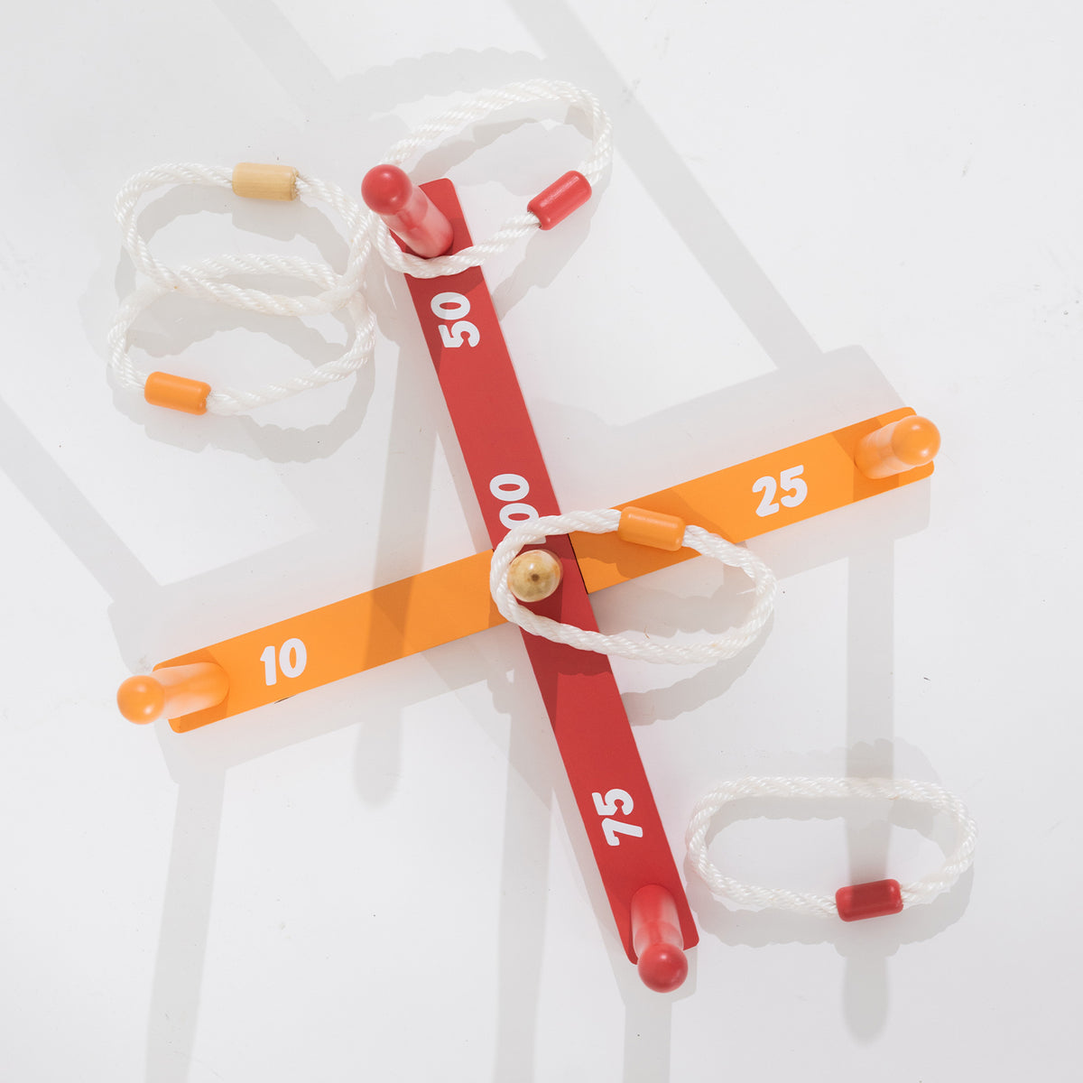 Overhead view of the wooden ring toss game with numbered red and orange scoring bars and white rope rings.