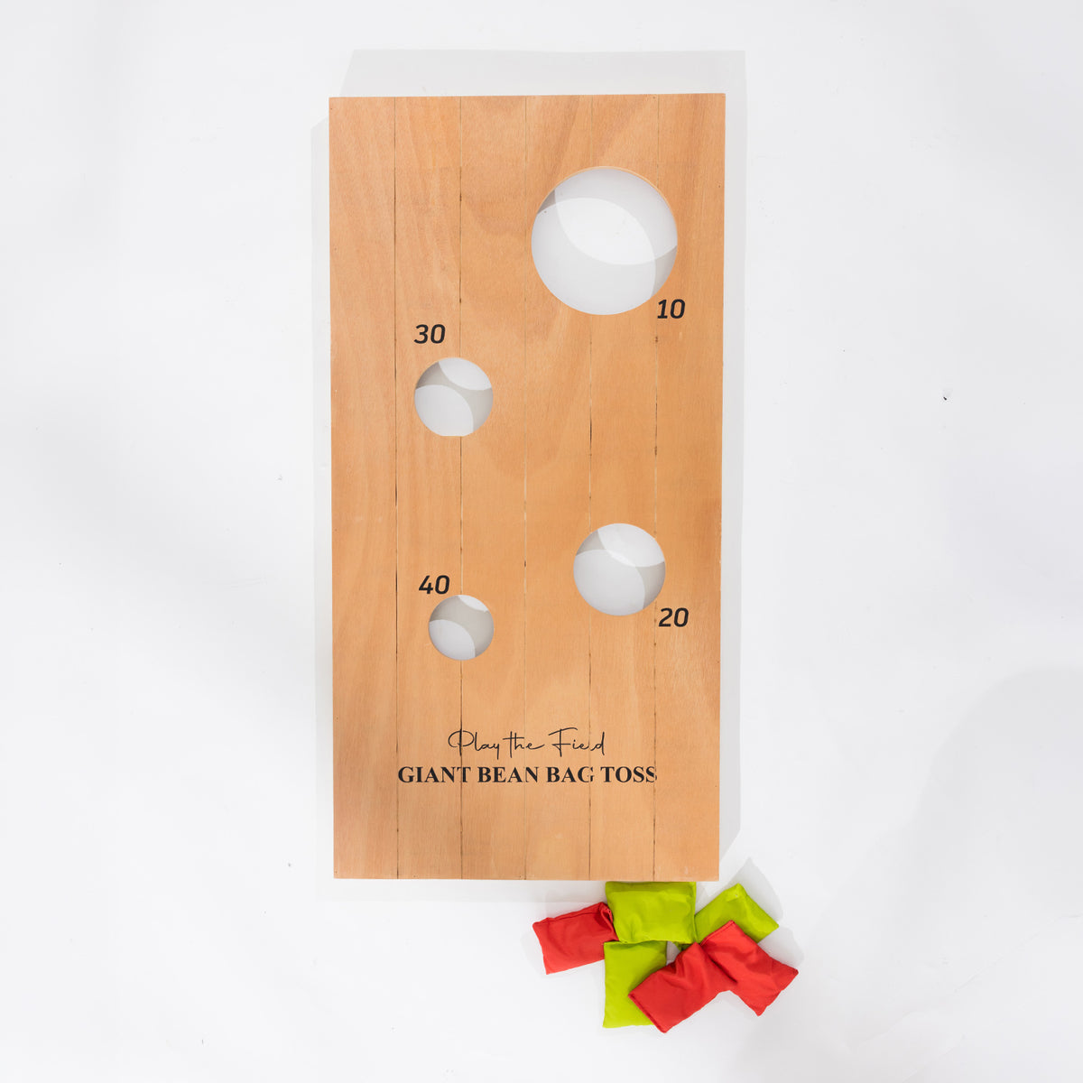Wooden Play the Field Giant Bean Bag Toss board shown flat with four scoring holes and red and green bean bags.