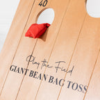 Close-up of the wooden Play the Field Giant Bean Bag Toss board with a red bean bag beside the 40-point scoring hole.